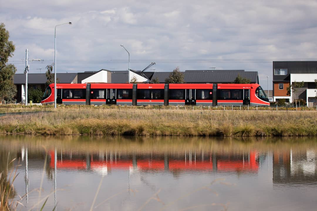 Side on shot of light rail vehicle going past stream in the Gungahlin area